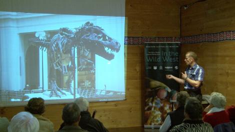 Mikael Siversson presenting a slideshow with a slide of a T-Rex fossil